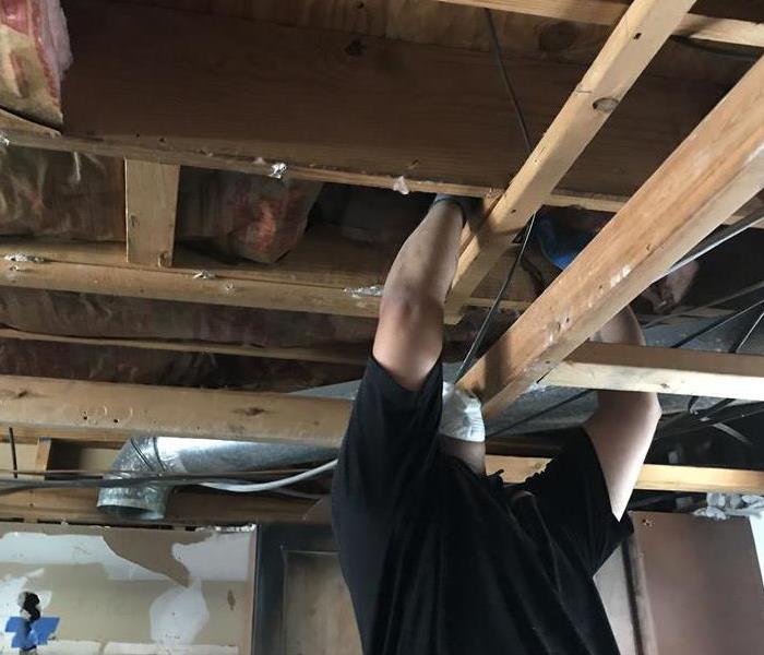 a man working on a ceiling with exposed wood beams