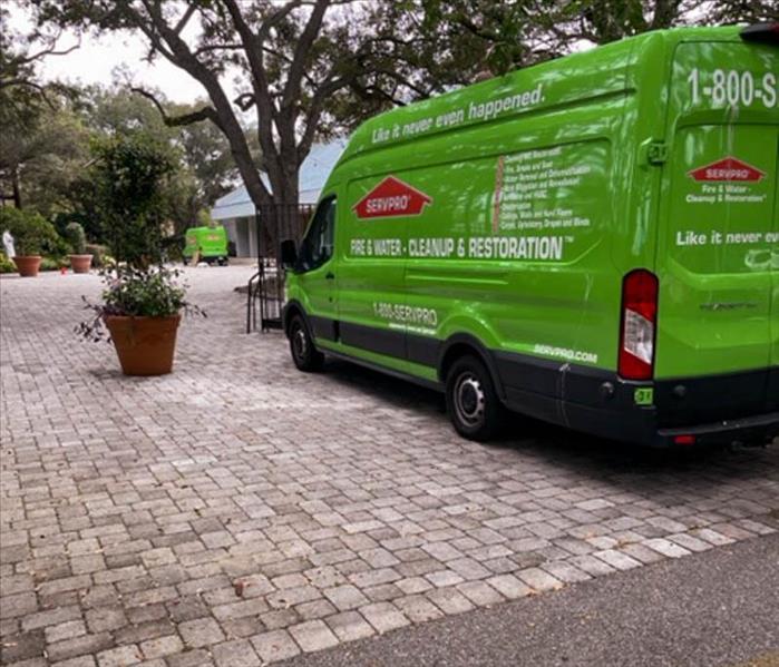 Green SERVPRO van parked outside a structure.